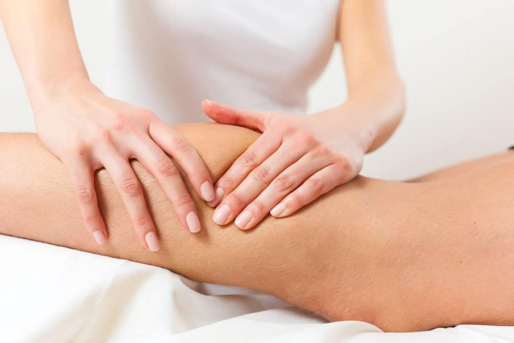 Массажист делает лимфодренажный массаж на ноге пациента